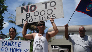 Activists hold signs opposing American marines on Guam