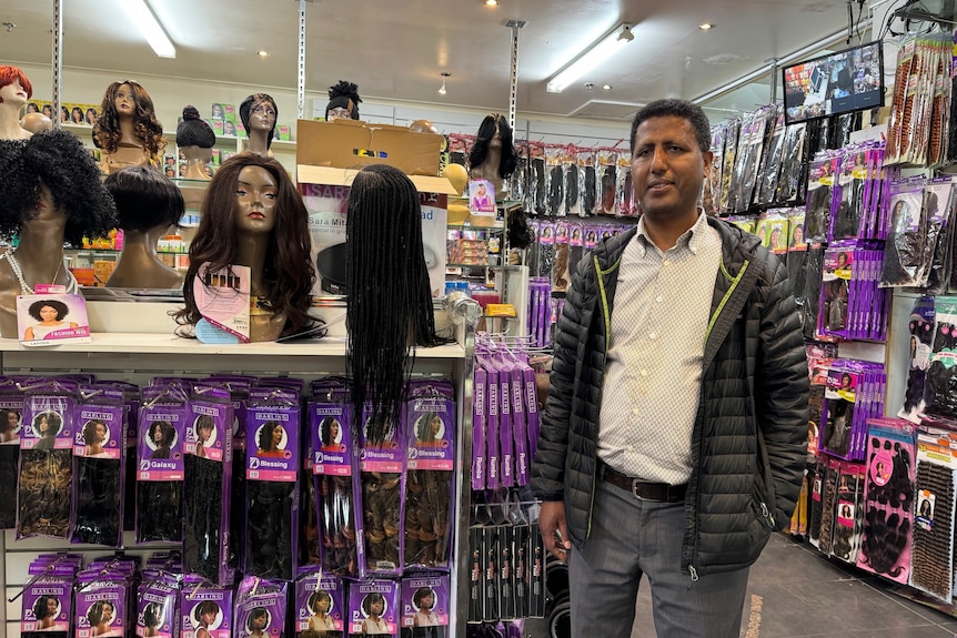Man stands in hair and cosmetics shop.