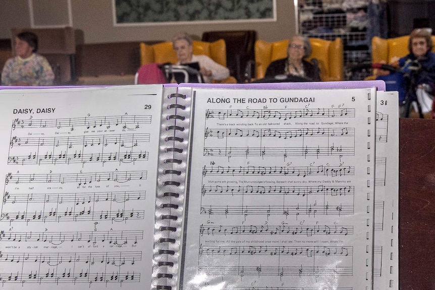 A folder showing songs, Daisy Daisy and Along the Road to Gundagai with elderly people in the background