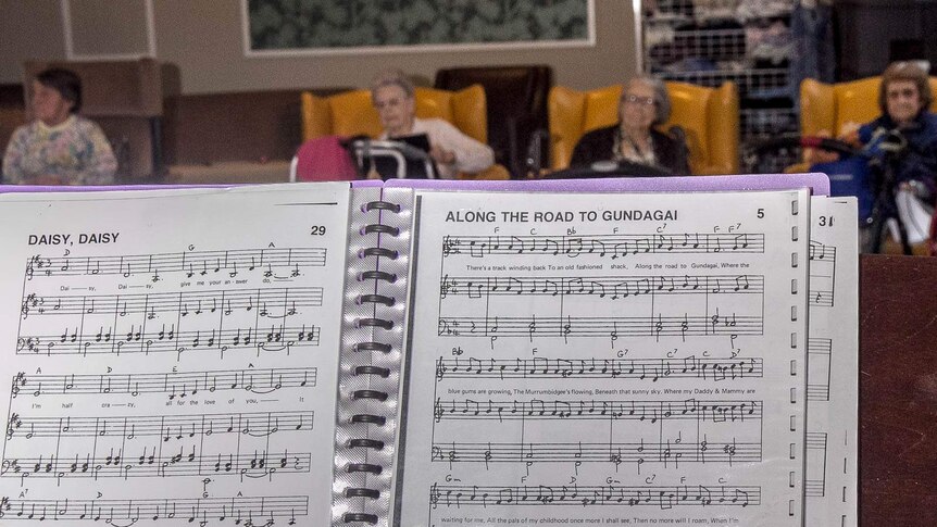 A folder showing songs, Daisy Daisy and Along the Road to Gundagai with elderly people in the background