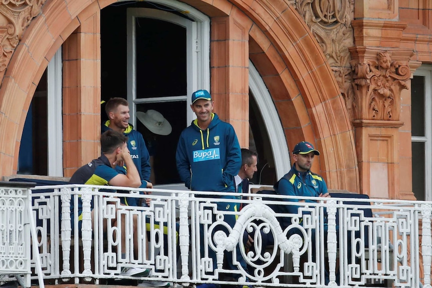 Justin Langer stands with David Warner, Nathan Lyon and Mitch Marsh on a balcony during a rain delay at Lord's.