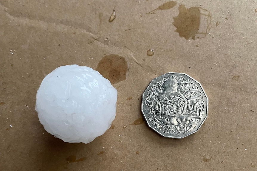 Large hail stone next to a 50 cent coin 