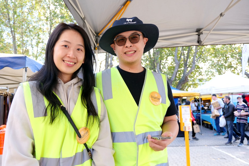 A woman and a man wearing high visibility vests stand together smiling.