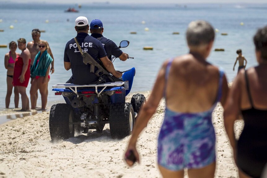Police on quad bikes patrol a Tunisian beach near the hotel where a gunman shot 38 people