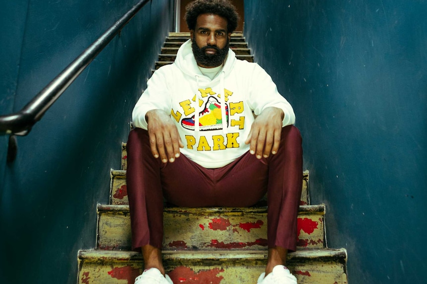 A man sits on a staircase and looks at the camera.