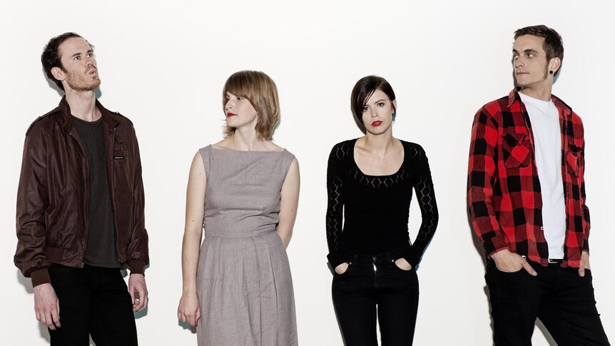 Four members of The Jezabels pose before a stark white background. Only Hayley looks at the camera.