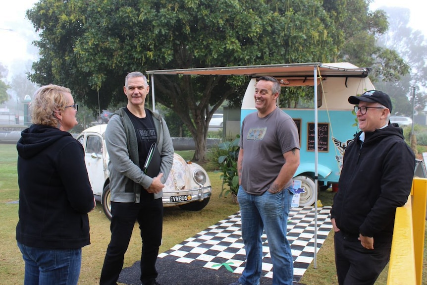 Four people stand together outside a a coffee  trailer.