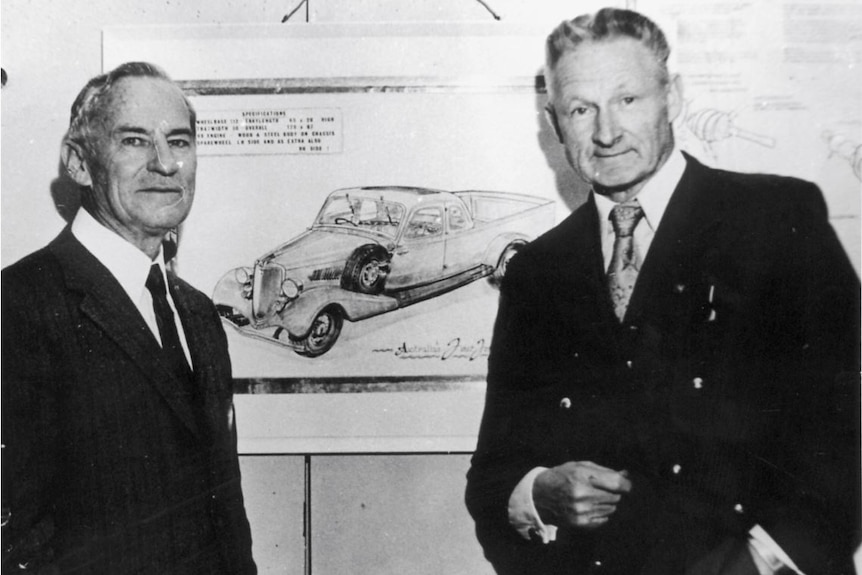 Image: Two men standing in front of a blueprint