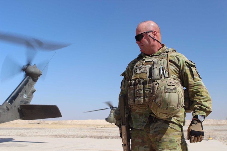 Brigadier Roger Noble in front of a helicopter in the desert.