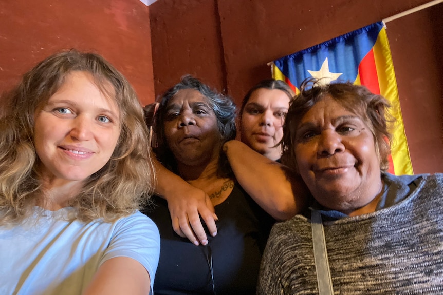 Four women smile at the camera in a "selfie", with one woman embracing her mother.