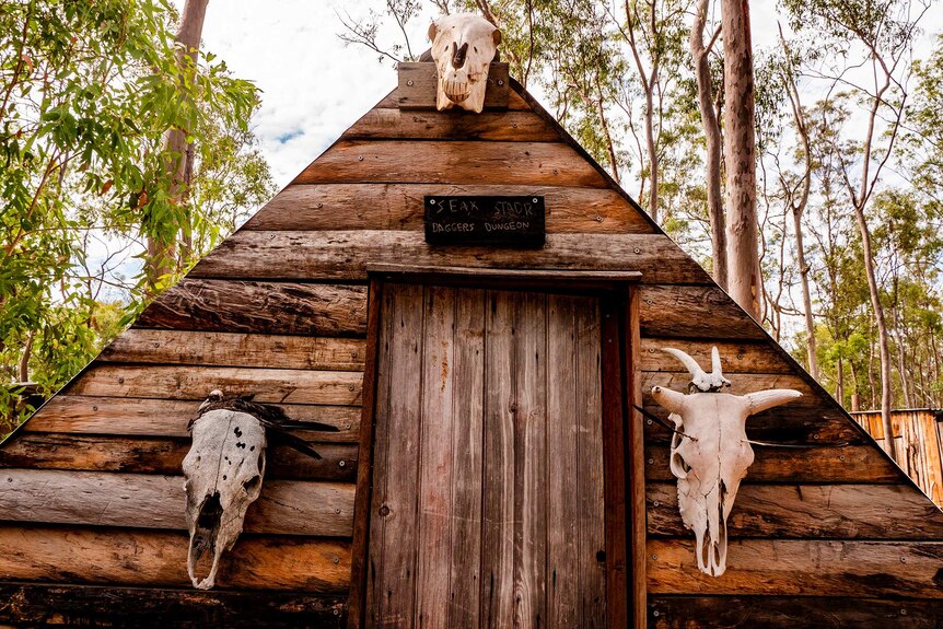 A timber triangle hut decorated with cow skulls.