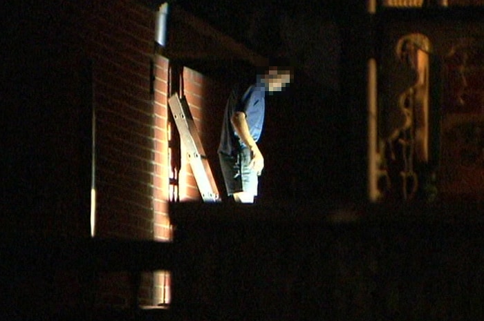 A man walking down a ladder from a roof at night