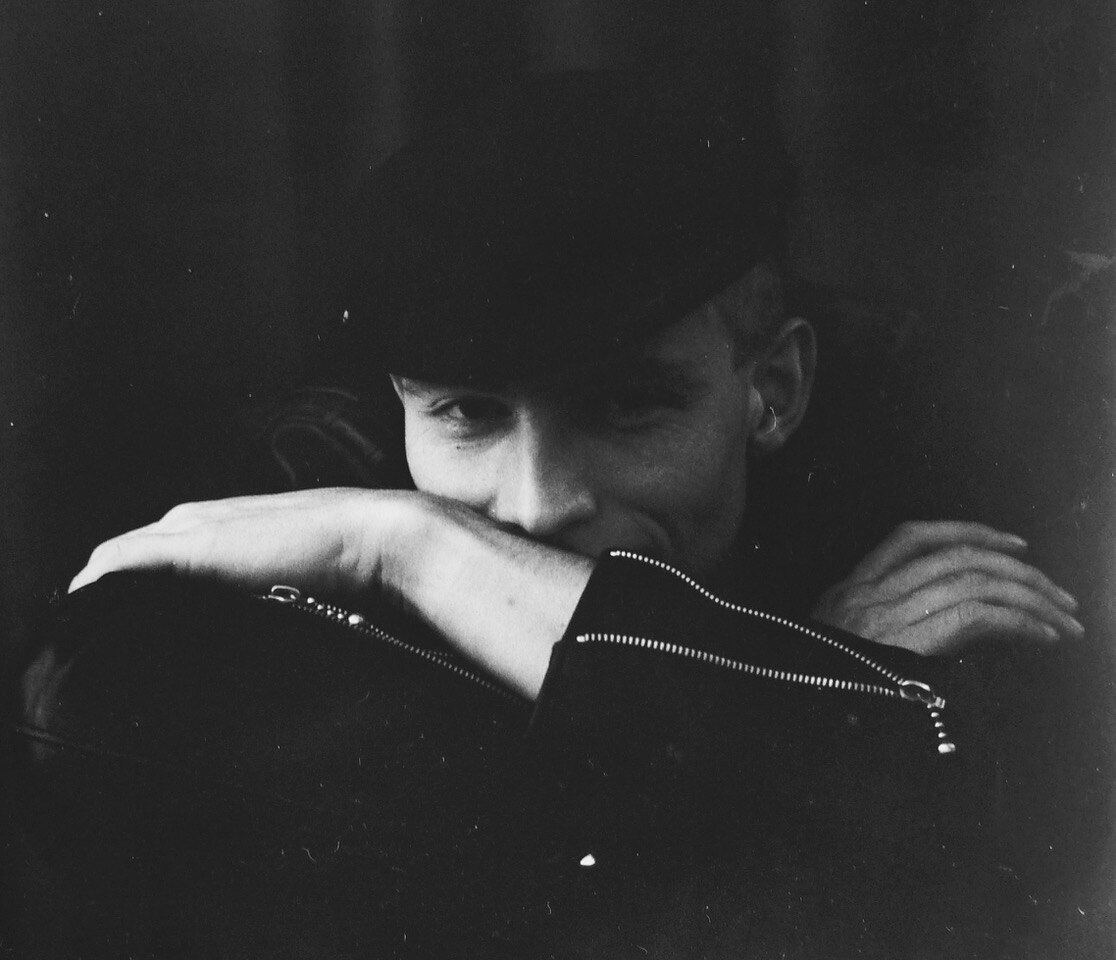 Black and white photo of a young Jerry Coleby-Williams wearing a black flat cap and half hiding behind his arms