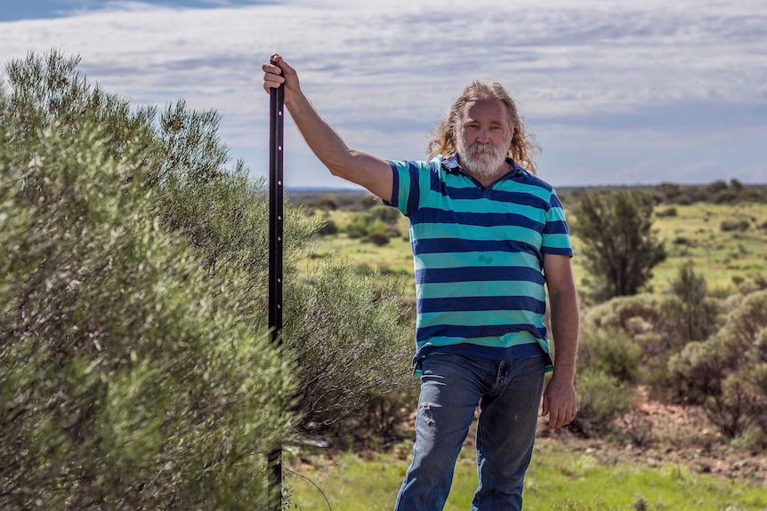 Roland Gopel standing on his land with trees and shrubs in the background.