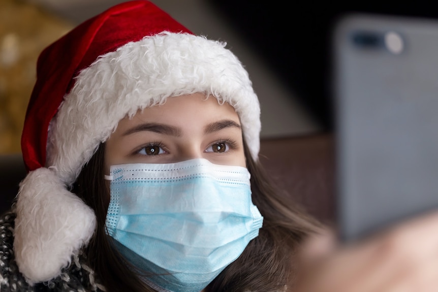 Woman wearing face mask and santa hat in COVID-19 pandemic. Cheif Health Officer says Queensland might need mask until Christmas