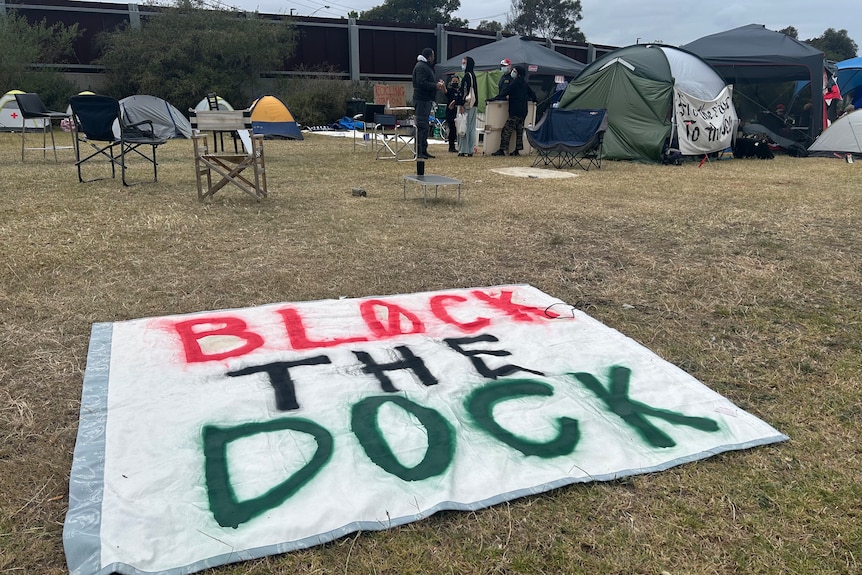 A sign on the grass near a campsite saying "block the dock".