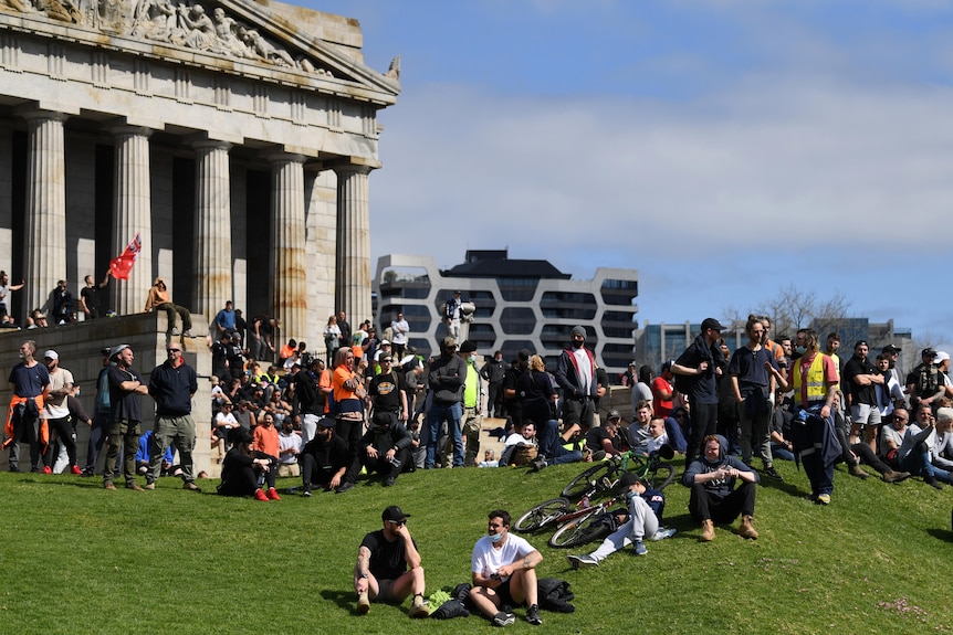 A crowd of protesters gather on the lawn in front of the Shrine of Remembrance.