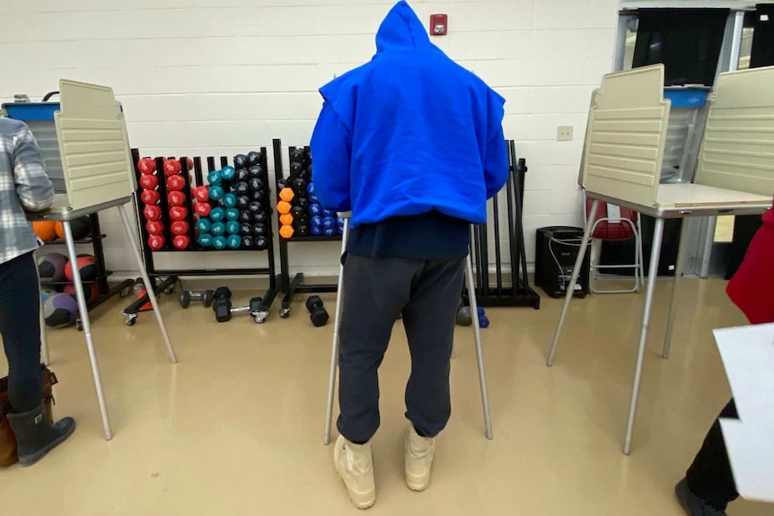 Man wearing blue hoodie and black track pants voting