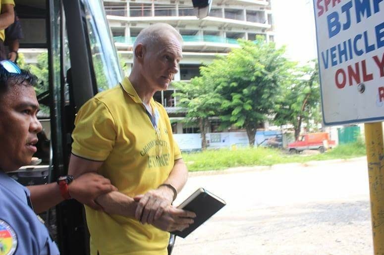 Peter Scully, in handcuffs, is led to court by authorities.