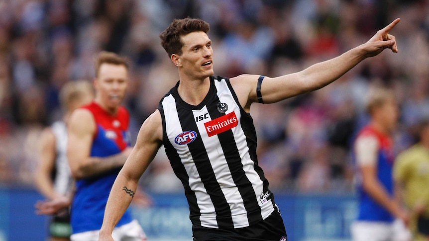 Brody Mihocek points a finger on his left hand as he celebrates kicking a goal for the Magpies.