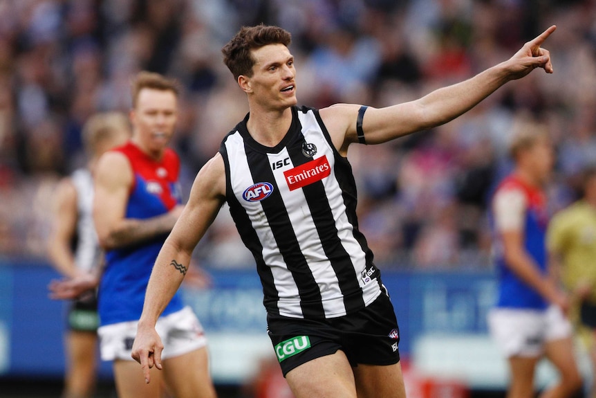 Brody Mihocek points a finger on his left hand as he celebrates kicking a goal for the Magpies.