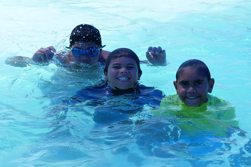 Three kids swimming in pool