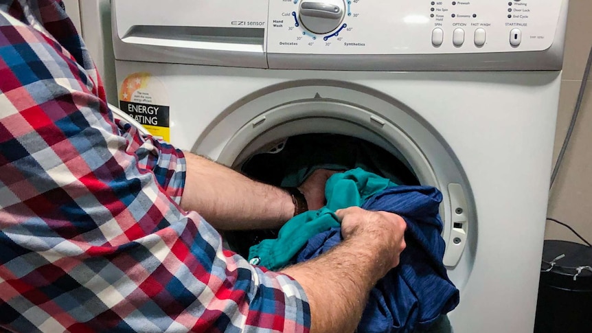 Man loading a washing machine.
