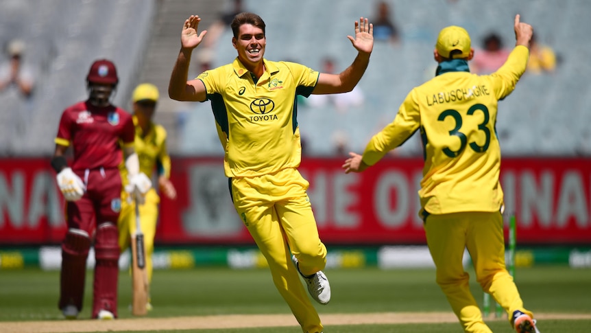 Australian fast bowler Xavier Bartlett grins as he runs toward a teammate with palms out for a high five after a wicket. 
