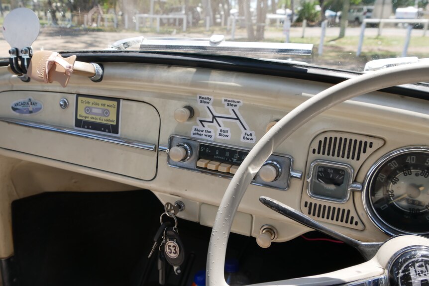 The cream vintage interior of a Volkswagen beetle. There is a sign for the gear stick with varying levels of slow.