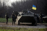 A tank with a Ukrainian flag raised above it.