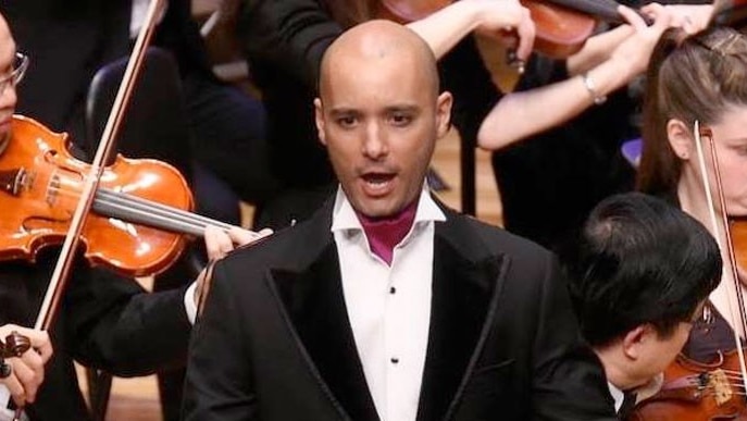 Shanul Sharma, in suit, singing in front of orchestra