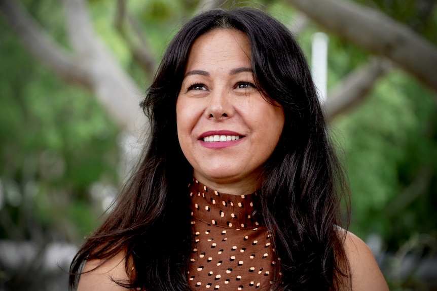 A woman standing in a park smiling 