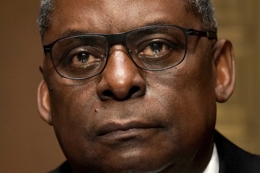 A close up of Lloyd Austin wearing a suit. His expression is serious.