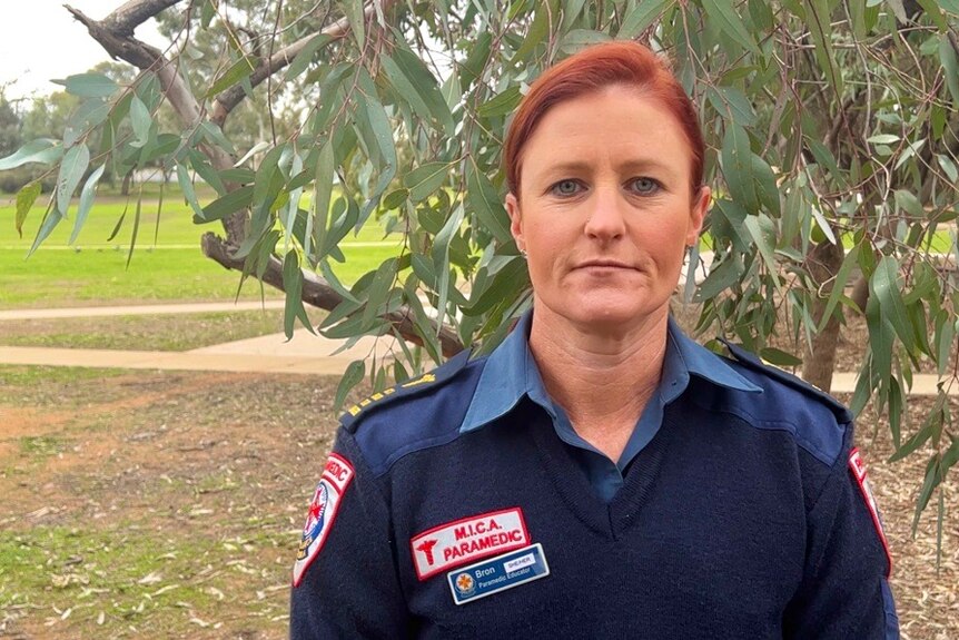 Paramedic in uniform with red hair looks down camera
