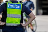 An image of an unidentifiable police officer whos head can't be seen, with their hands on their hips wearing a high vis vest.