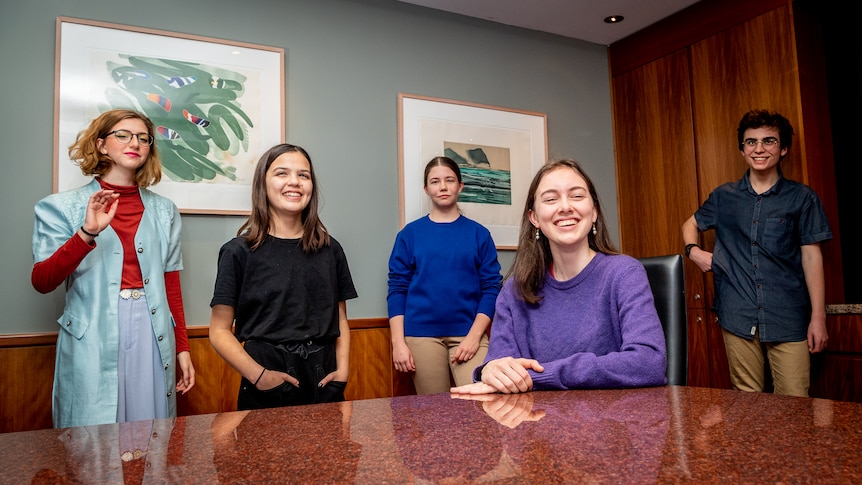Five teenagers in a boardroom setting