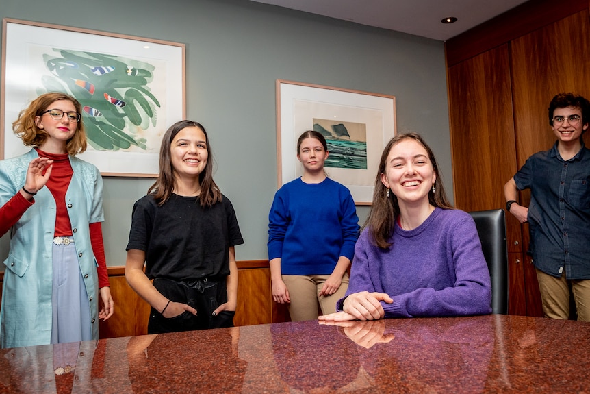 Five teenagers in a boardroom setting