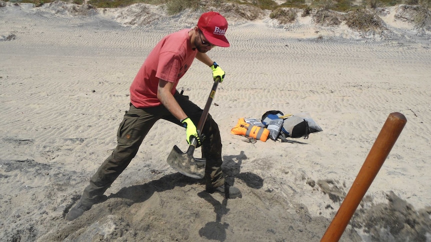 Dr Milo Barham digging for mineral samples on a south coast beach