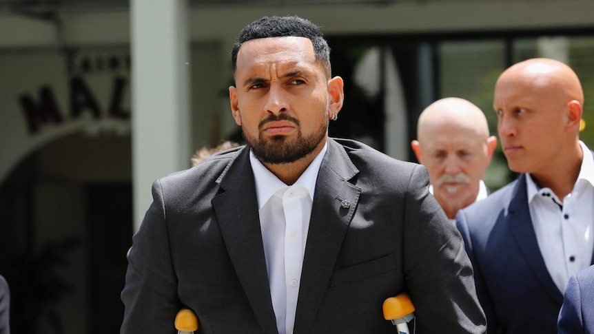 Nick Kyrgios walks out of court, assisted by crutches.