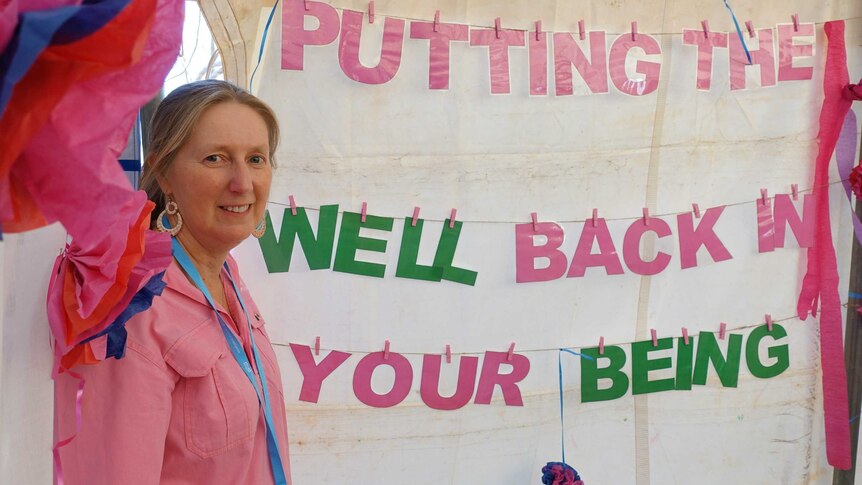 Karen Sherlock with a 'putting the well back in your being' sign