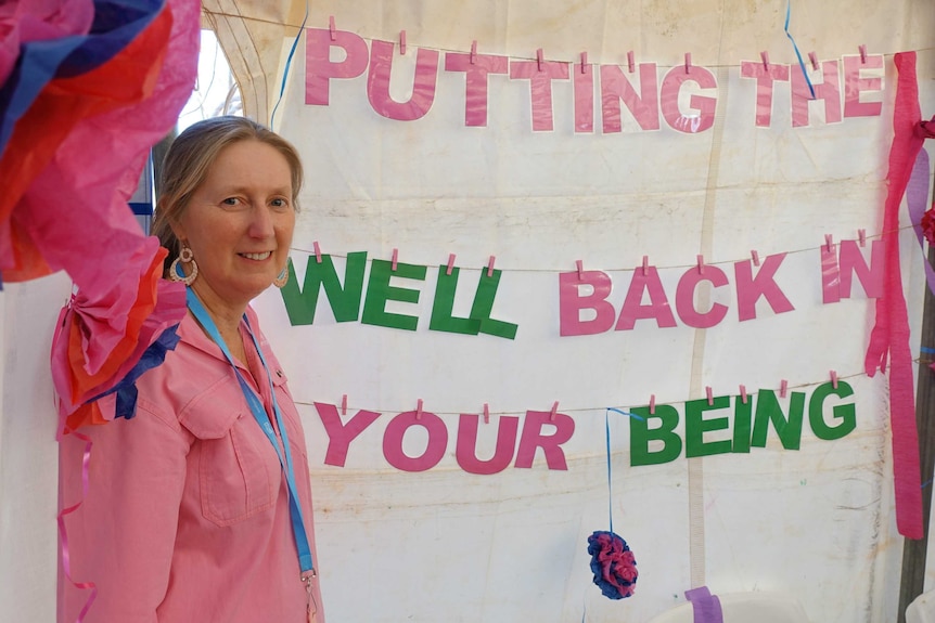 Karen Sherlock with a 'putting the well back in your being' sign