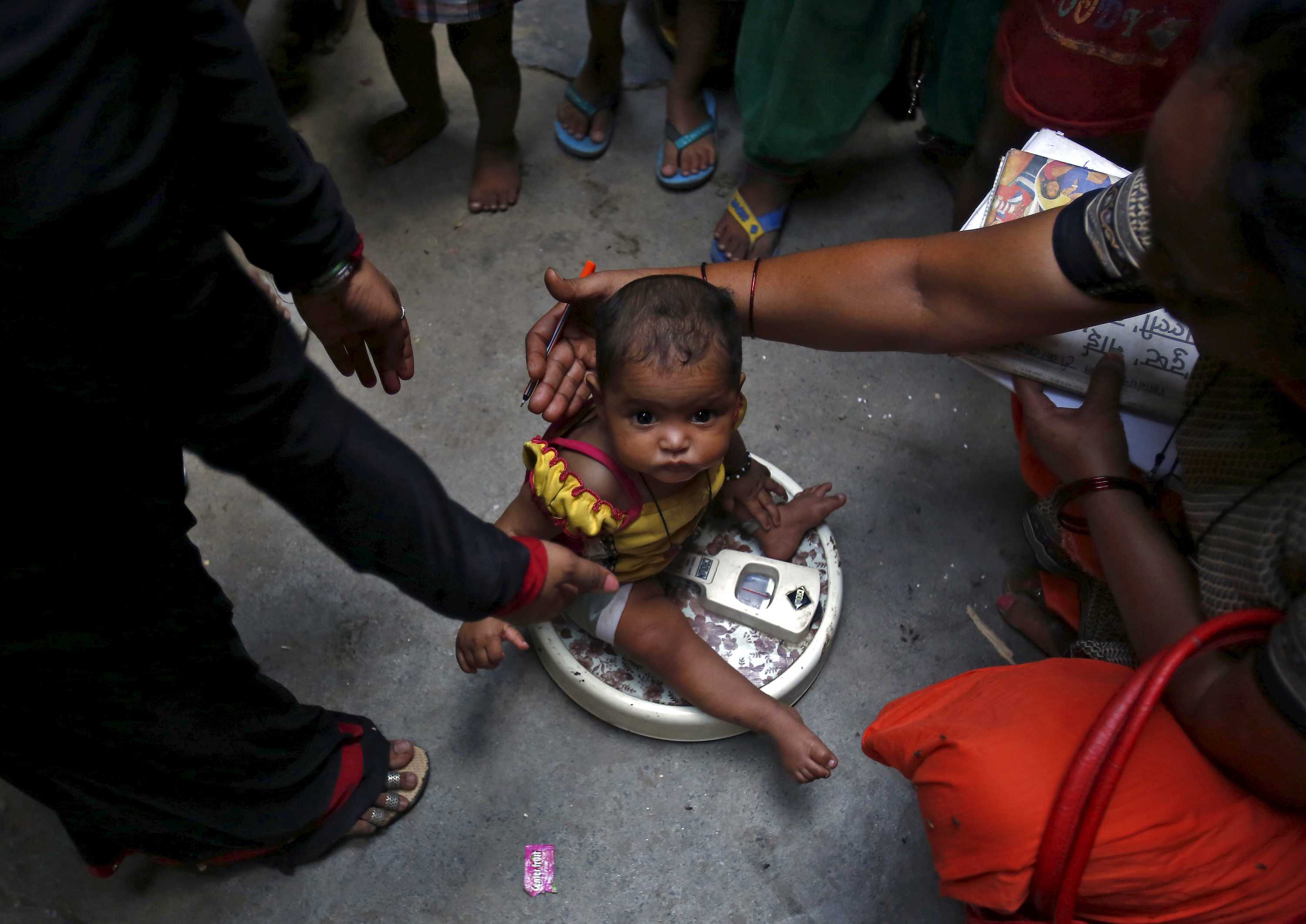 A health worker weighs a child under a government program in New Delhi.