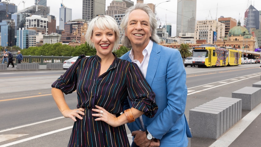 A portrait of ABC presenters Jacinta Parsons and Brian Nankervis with a Melbourne tram in the background.
