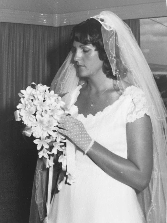 An archival photo of a woman in her wedding dress, holding her bouquet.