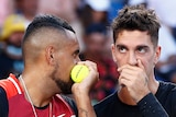 Two Australian male tennis players chat during a doubles match.