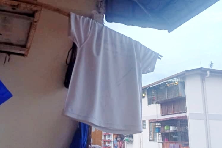 A white flag made out of a white t-shirt hanging on a balcony