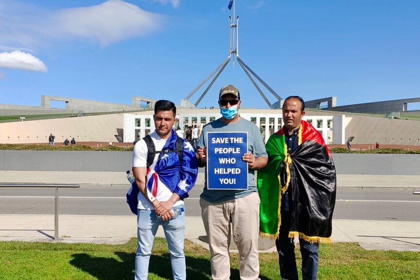 Three Afghan men stand in front of palriament house in Canberra.