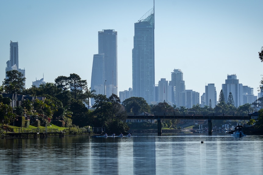 A four-person kayak on a canal in the shadows of skyscrapers that make up the Gold Coast skyline.