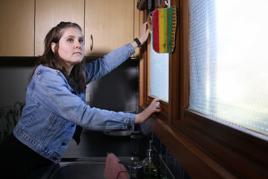 A Canberra resident sticks bubble wrap to the windows above her kitchen sink.