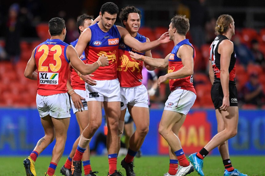 Brisbane Lions AFL players celebrate in a group after a goal was kicked against Essendon.